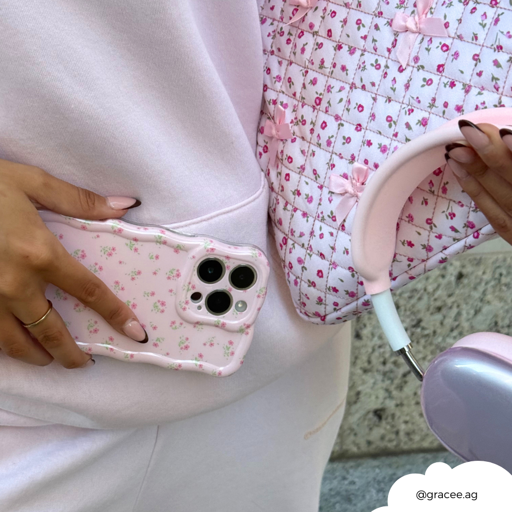 Person in pink holds a Ditsy Floral Pink wavy phone case, a quilted pink bag, and pink headphones.