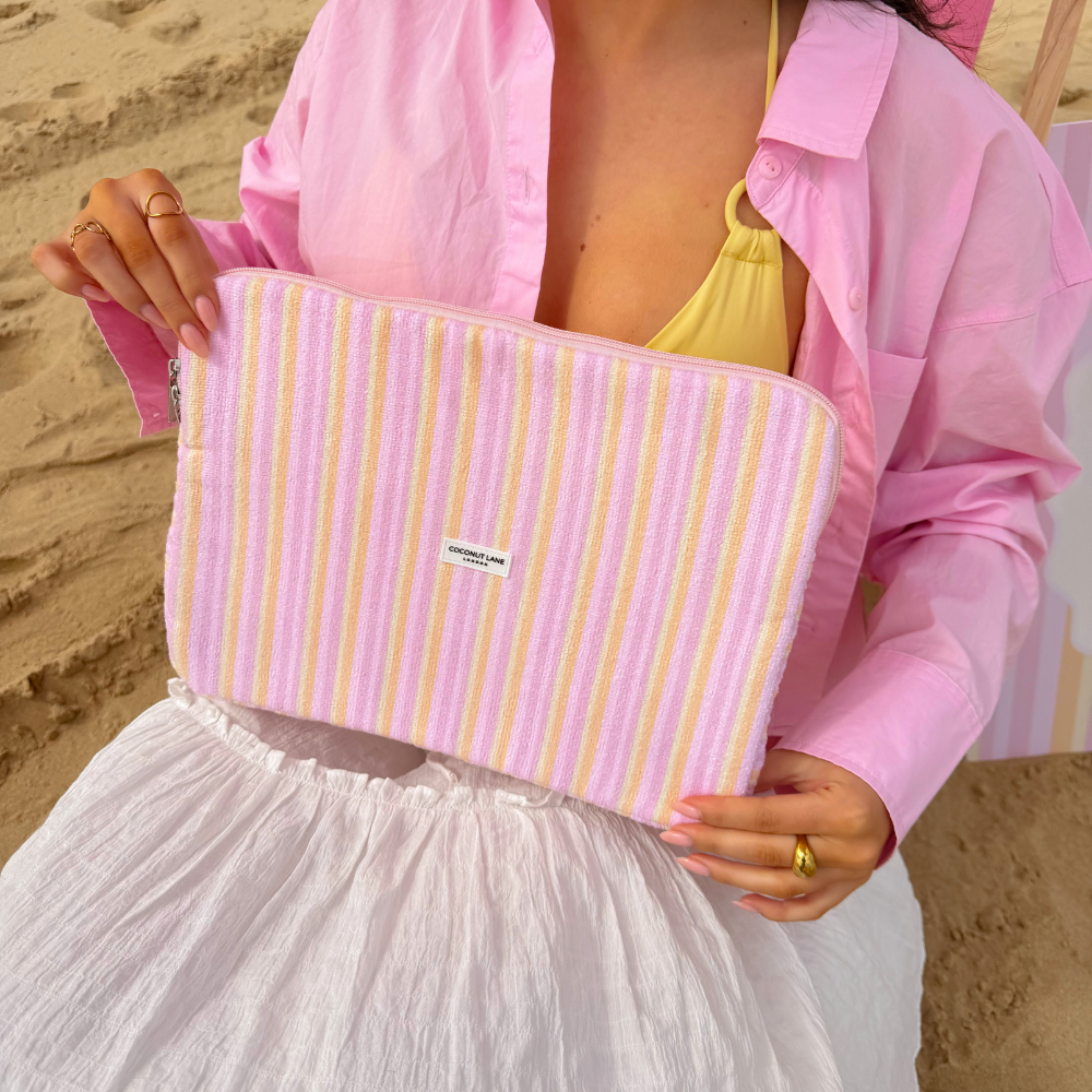 Girl sat in pink deck chair holding her pastel stripes laptop sleeve