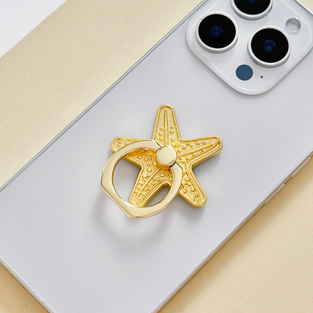 Silver smartphone with a Coconut Lane adhesive phone ring featuring a starfish design.