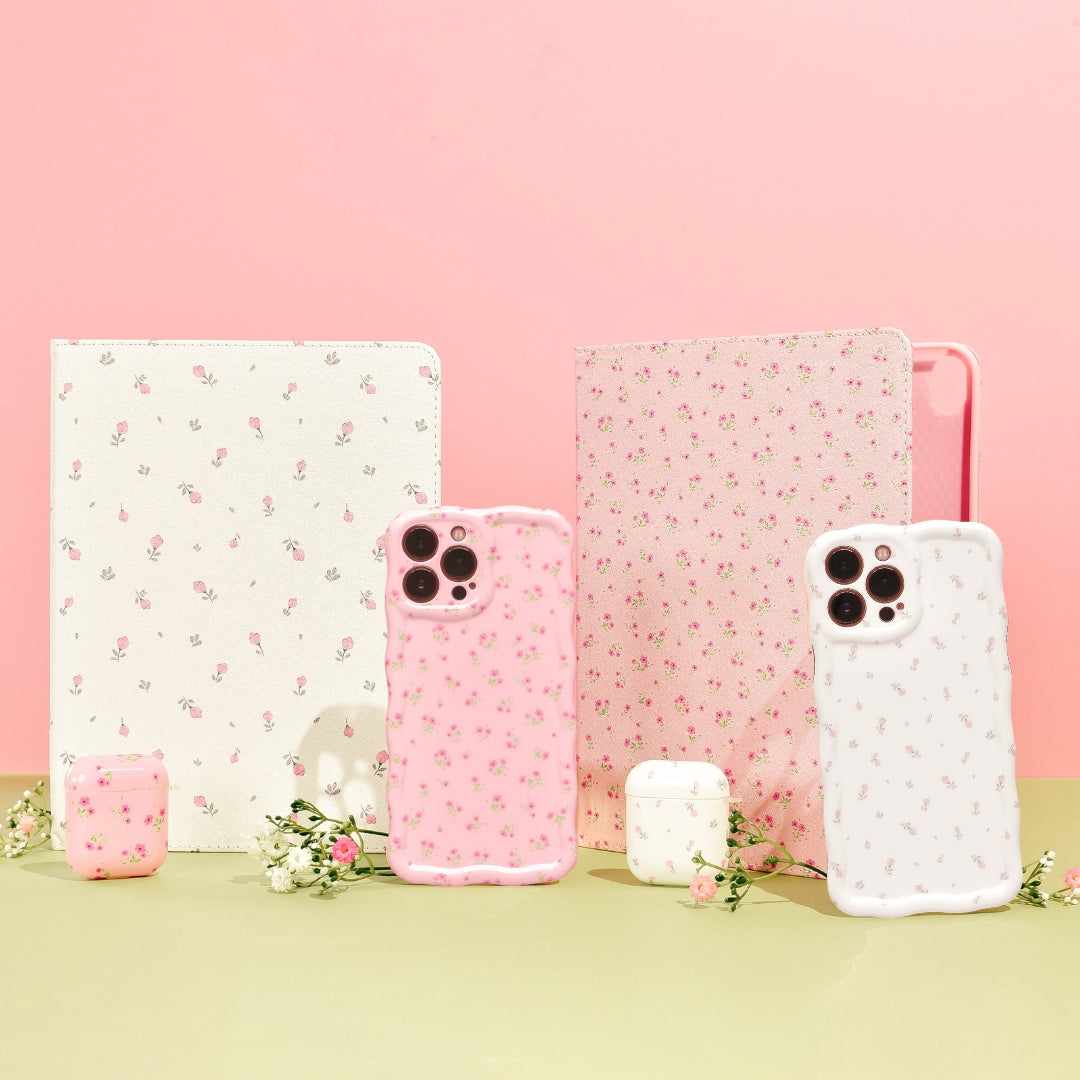 A pink smartphone case with a delicate floral pattern is placed on a contrasting darker pink background. Small white and pink flowers are scattered around the phone case, enhancing the aesthetic appeal of the image.