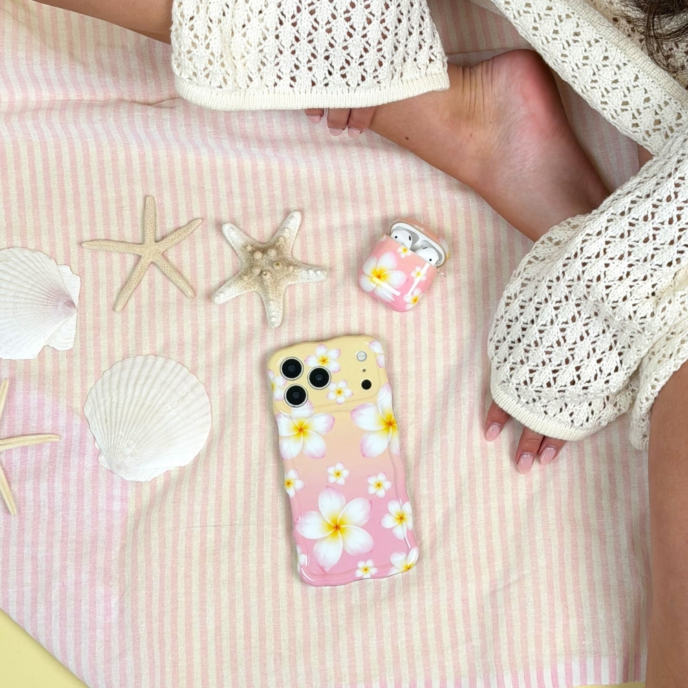 Phone case and Airpods case with floral Aloha Bloom design on a pink striped towel with starfish and shells.