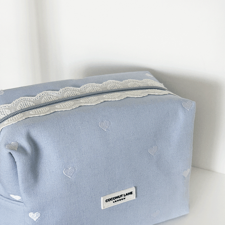 Blue fabric Makeup Bag with embroidered heart design and white lace trim.