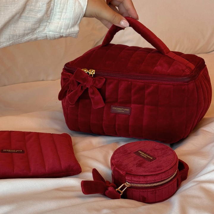 Burgundy velvet cosmetic bag , jewlerry box and pouch with a quilted design, top handle, bow detail, and gold-tone hardware.