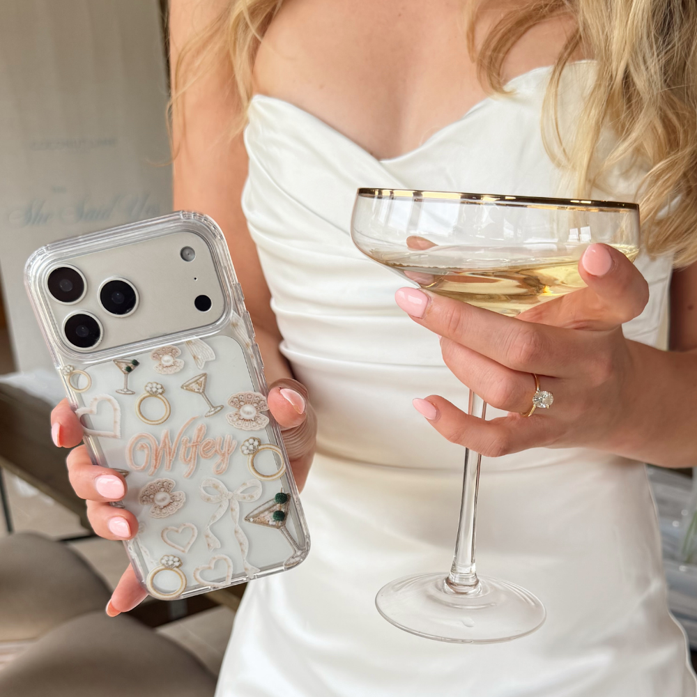 Girl holding a phone case with 'Wifey' and a glass of wine.