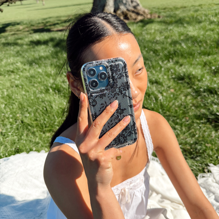 Girl at a picnic showing off her black lace phone case