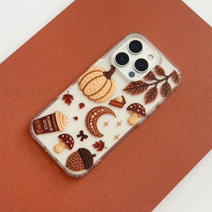 A clear phone case decorated with autumn-themed graphics including a pumpkin, moon, mushrooms, acorns, stars, and leaves.