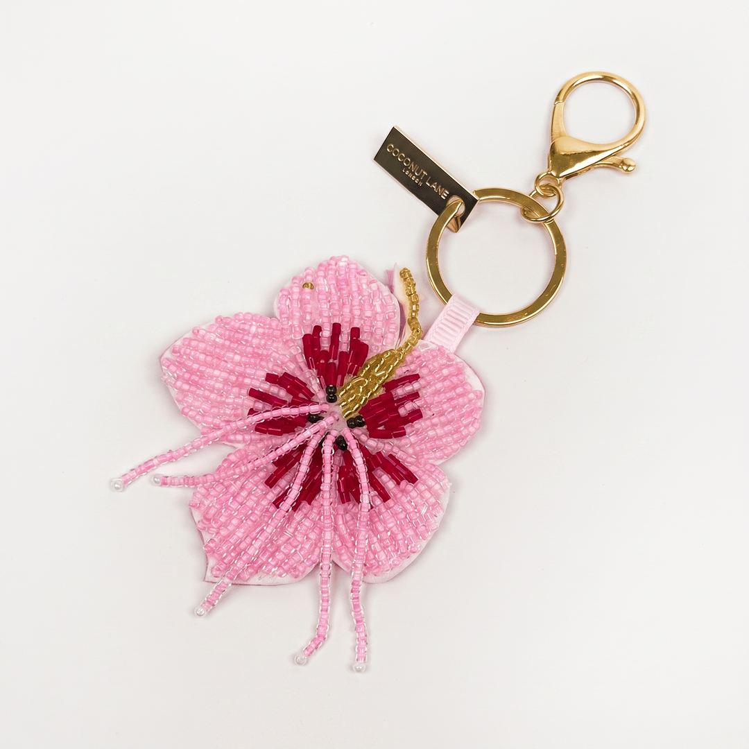 A pink beaded flower keyring with a gold-tone split ring and lobster clasp, shown on a plain white background.