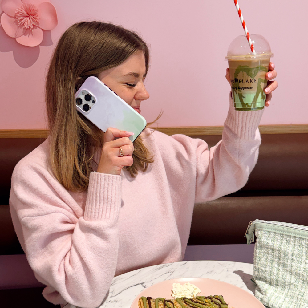 Girl in a pink jumper holding her matcha whilst on the phone with the phone case Lavender Tough Phone Case