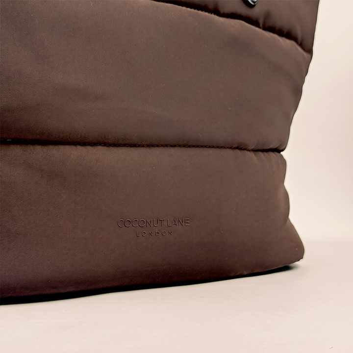 Close-up of the chocolate brown padded carryall bag, highlighting the silicone raised logo.