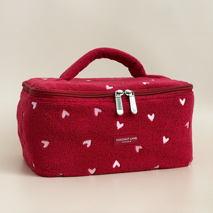 Red cosmetic bag with white heart patterns on a beige background