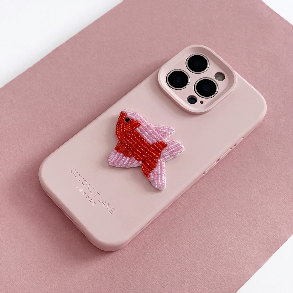 Red and pink 3D fish made from beads and sequins, on top of a pink Coconut Lane Phone Case. 