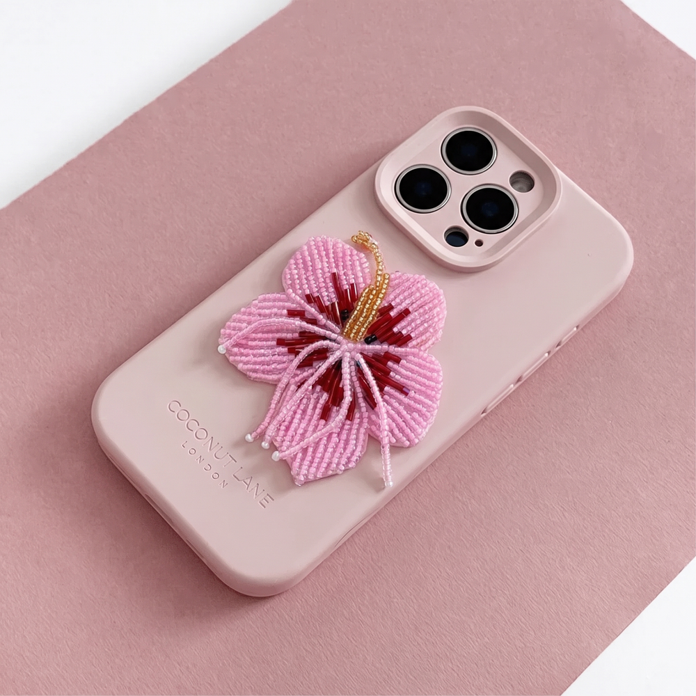 Pink 3D hibiscus flower made from beads and sequins, on top of a pink Coconut Lane Phone Case. 