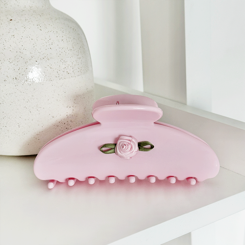 Pink hair claw clip with a small rose embellishment and green ribbon accent.
