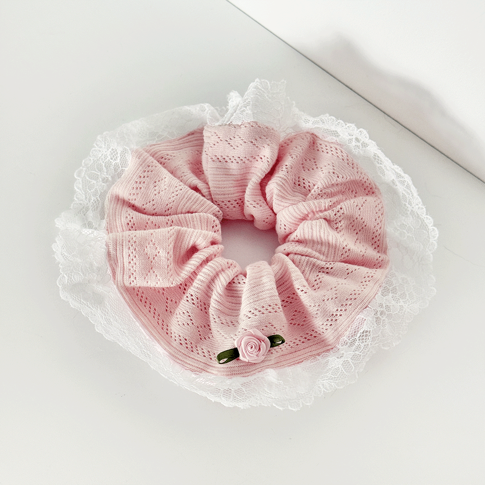 Pink pointelle fabric hair scrunchie with hite lace trim detailing and rose embellishment.