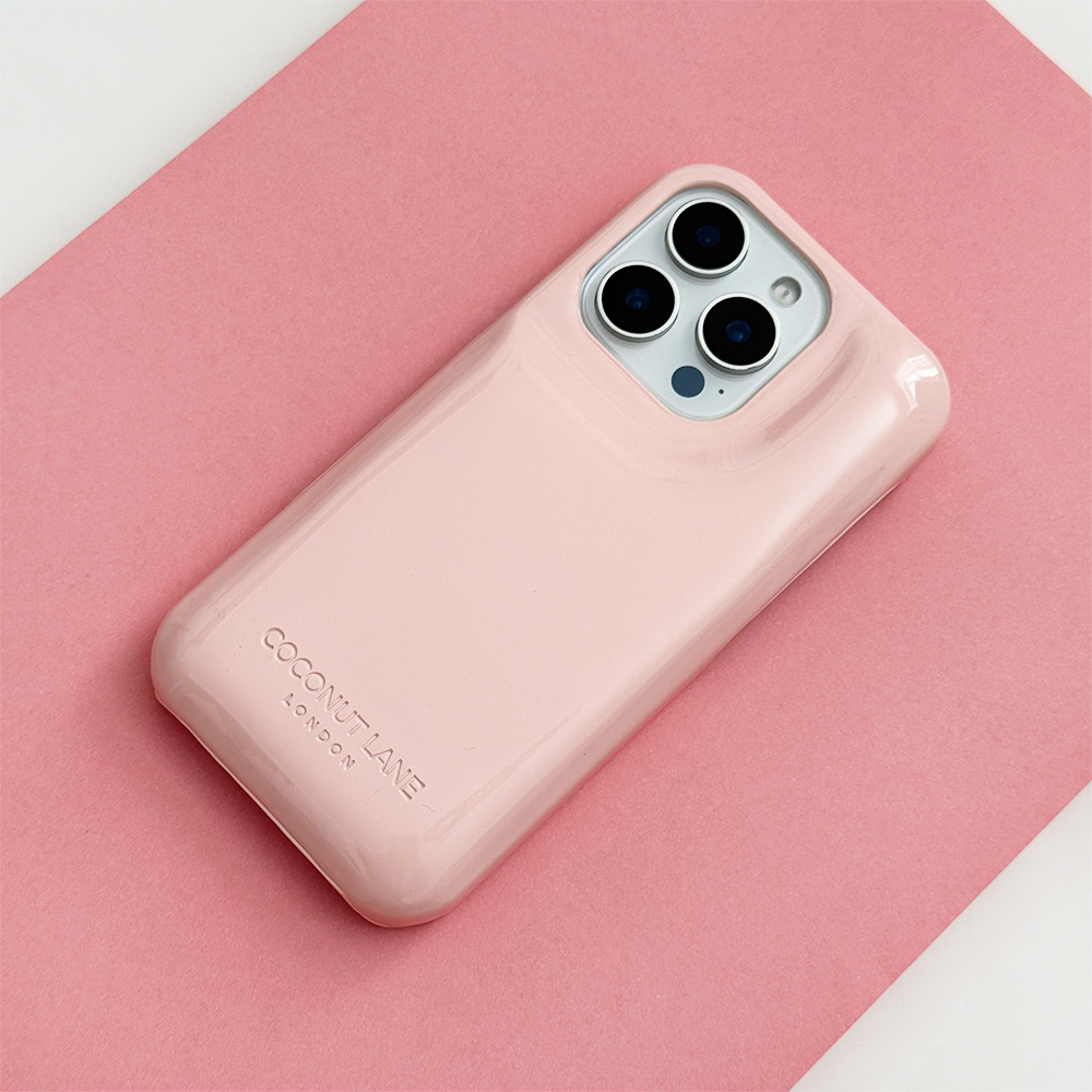 Glossy pastel pink Coconut Lane puffer phone case with embossed logo, displayed diagonally on a matching pink background.