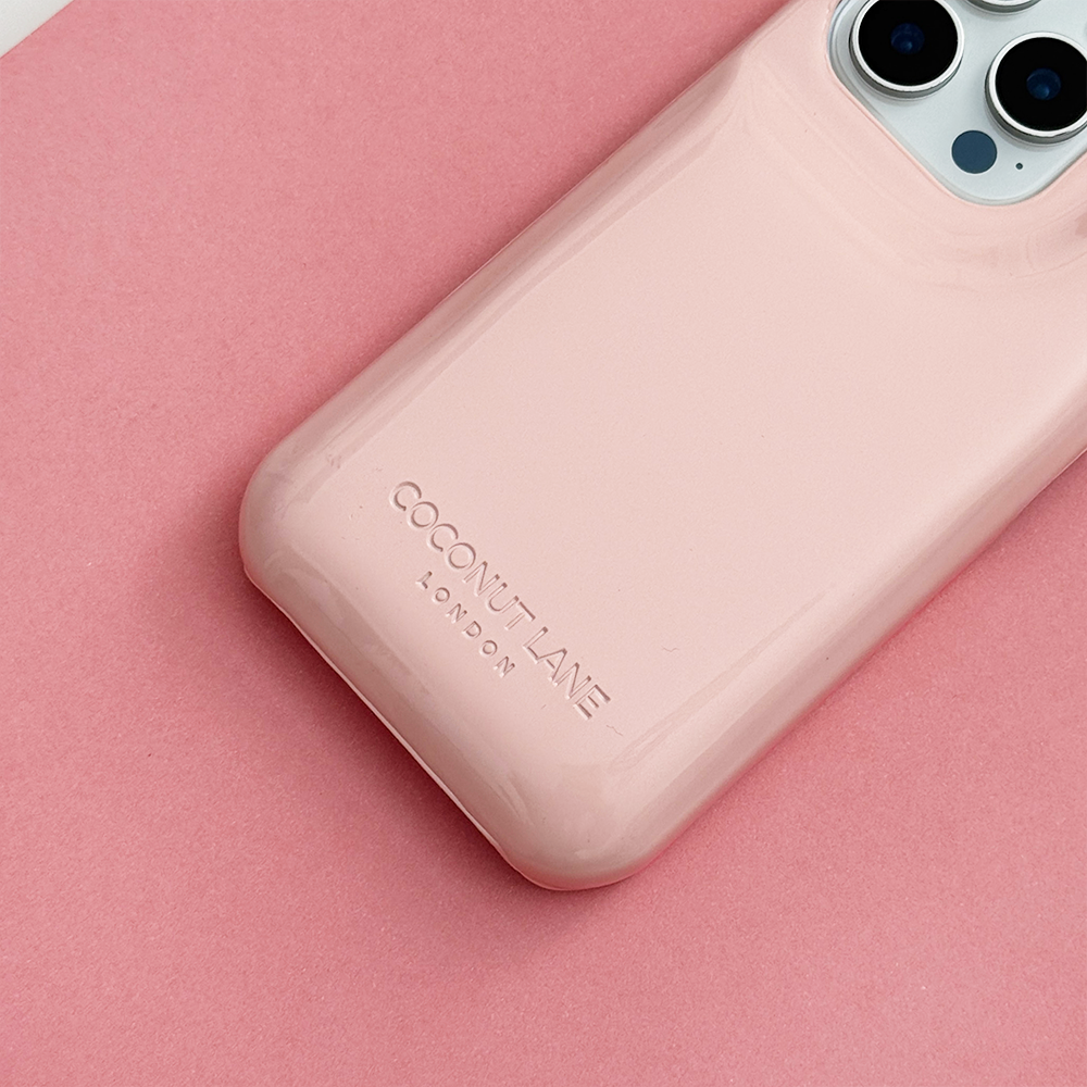Close-up of glossy pastel pink Coconut Lane puffer phone case with embossed logo, displayed diagonally on a matching pink background.