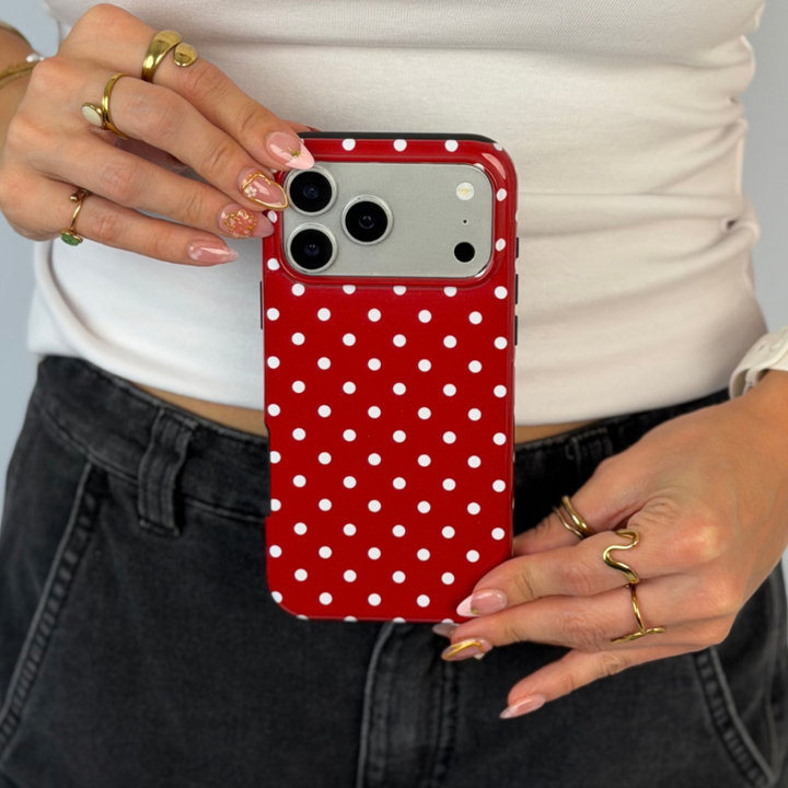 Woman holding an iphone, with a red and white polka dot phone case. 