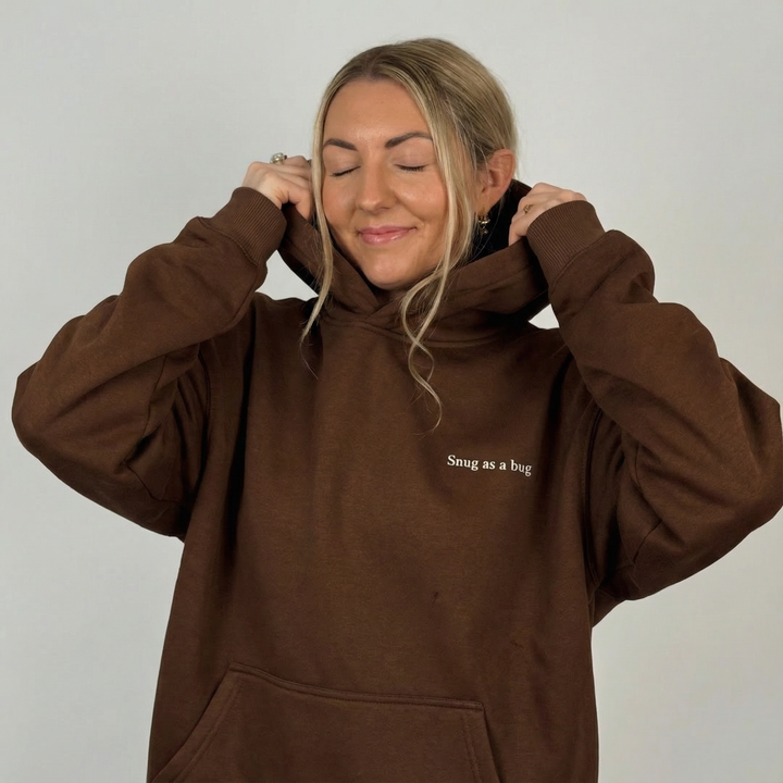 Person wearing a brown hoodie with 'Smug as a bug' text on a plain background