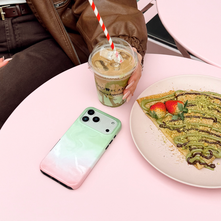 Tough Strawberry Matcha Phone Case on a pink table next to girl holding matcha and a place of pancakes