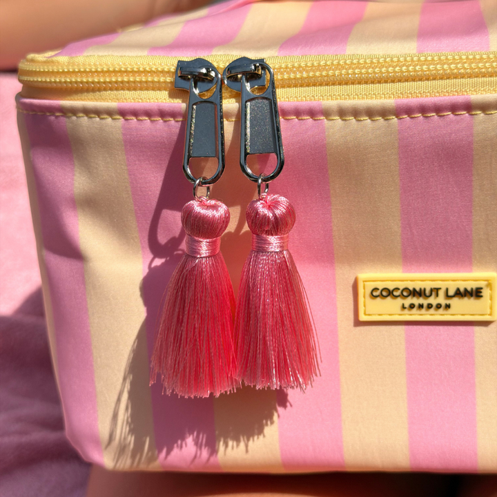 Pink tassel on a pink and yellow striped vanity case with 'Coconut Lane London' label.