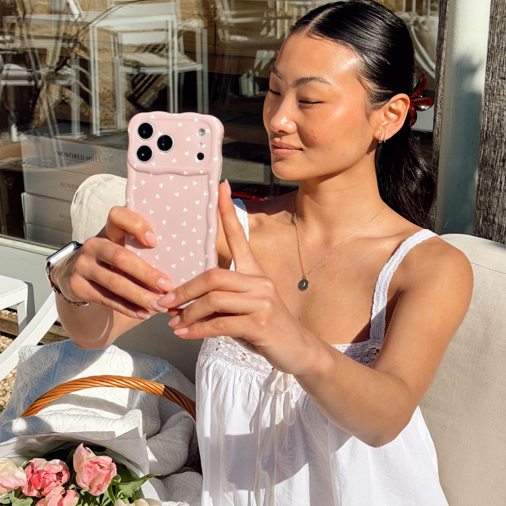Girl smiling taking a selfie in the sun with her Chai Hearts Phone Case