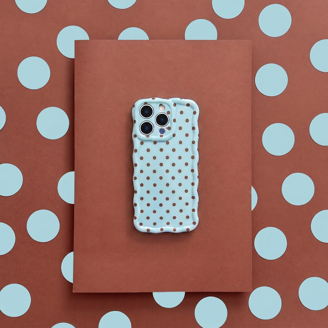 Phone case with polka dot pattern on a brown surface with blue polka dots