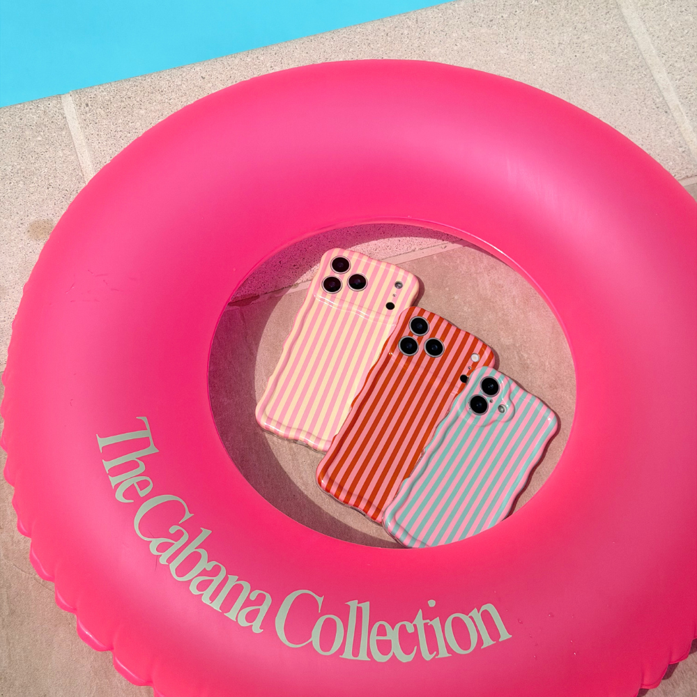 Pink inflatable ring with 'The Cabana Collection' text, containing striped phone cases.