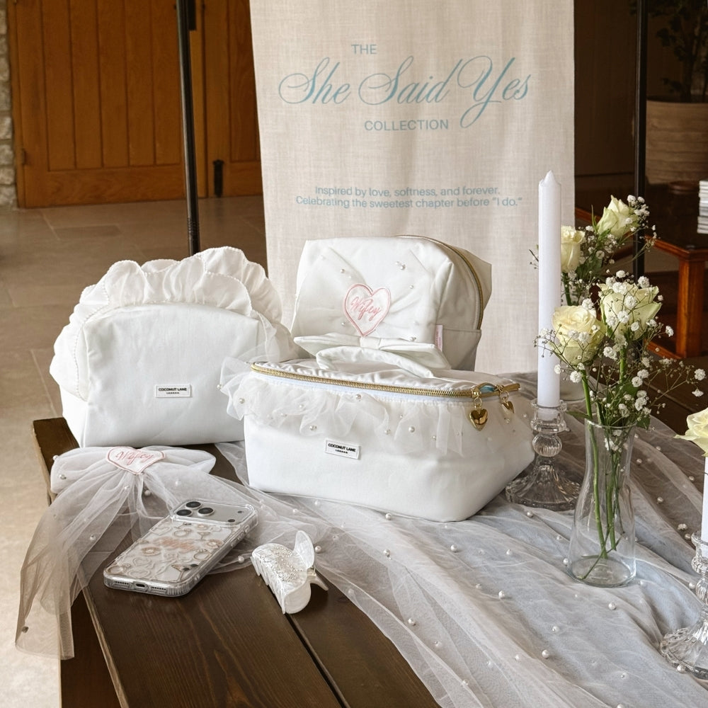 Group image of bridal phone case, makeup bags, hair bow at a wedding setup.